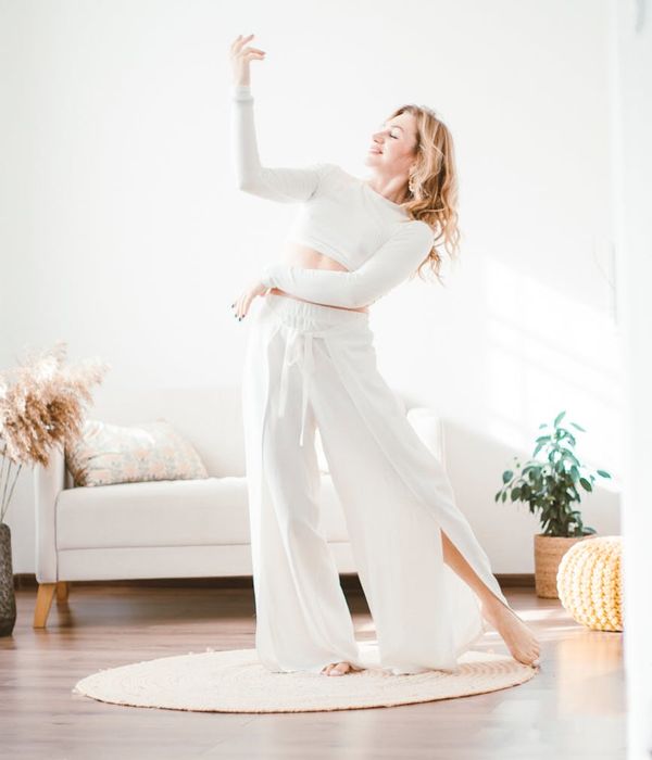 Woman performing a light cardio movement in a bright living room.